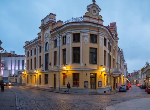 Pildil on Eesti Noorsooteatri hoone, mis asub Tallinna vanalinnas Laia ja Nunne tänava nurgal. Tegu on ajaloolise kolmekorruselise kollakat värvi hoonega, mida on pildil kohtvalgustitega valgustatud.
