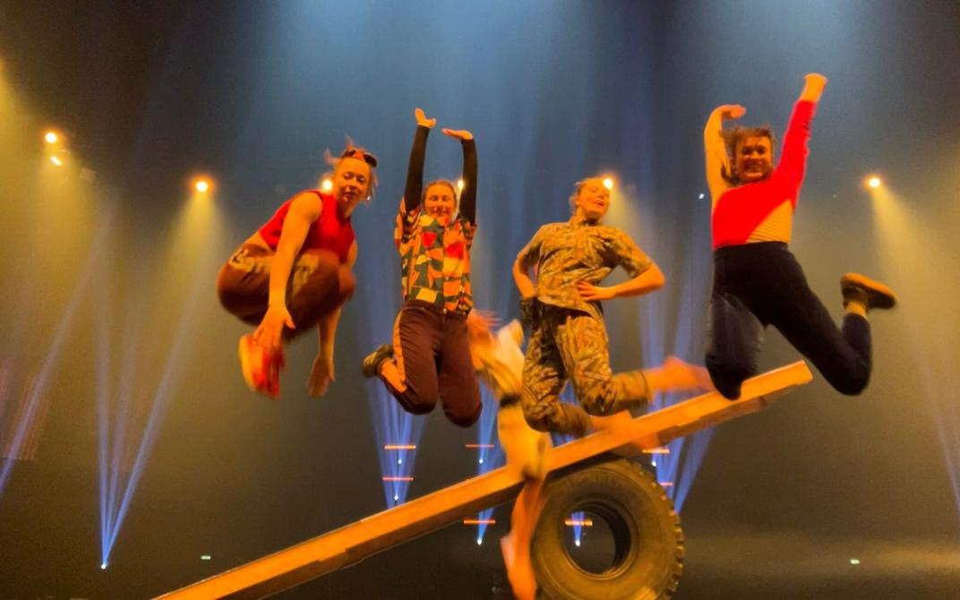 Pildil on neli noort naist, kes hüppavad laval õhku.
