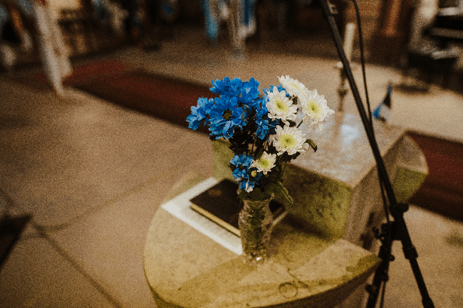 Pildil on kõnepult, millele on asetatud vaas siniste ja valgete lilledega.