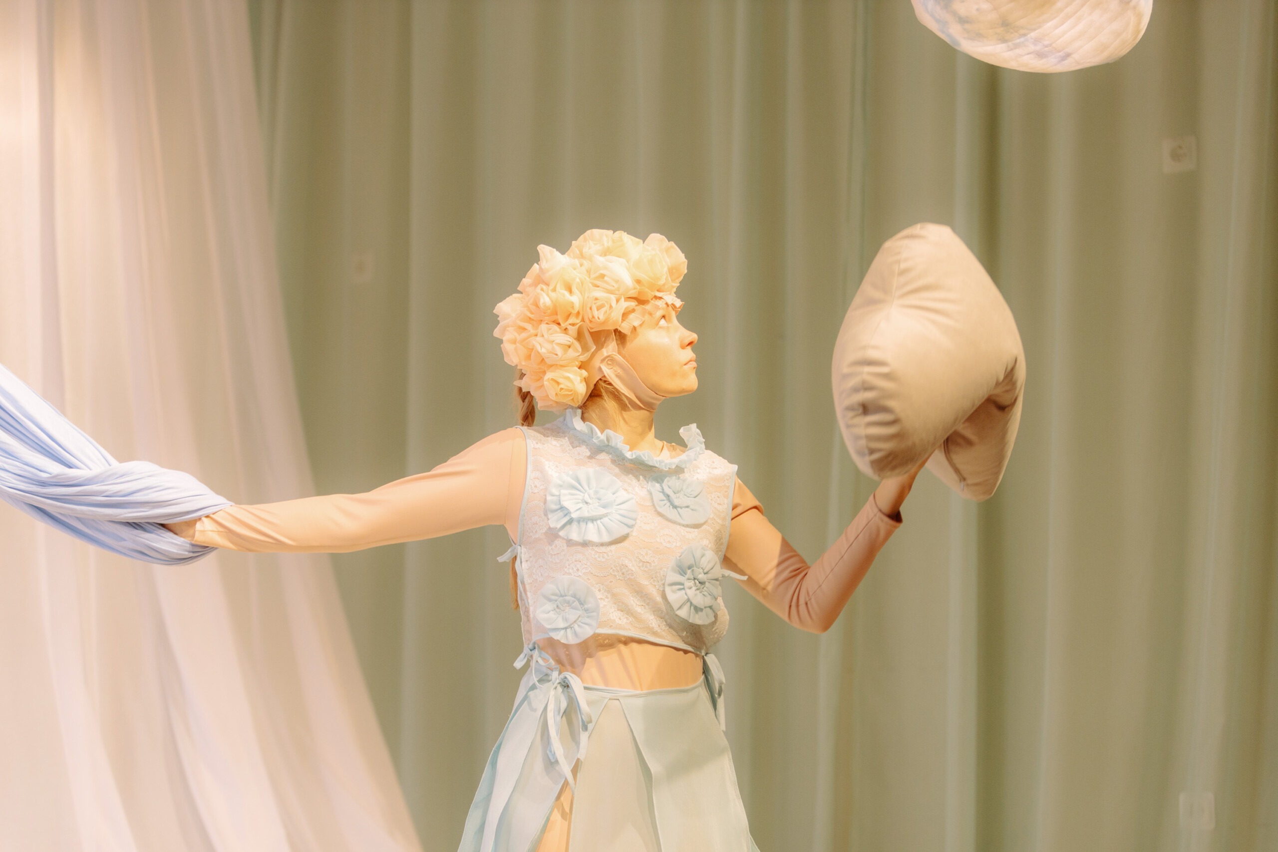 Pildil on Doris Tislar lavastuse "Sansaara" osatäitjana. Tal on seljas helesinine ja -beež õhuline kostüüm, peas hele kangast roosidega müts. Tema käes on pilvekujuline padi, taustal heledad kardinad.
