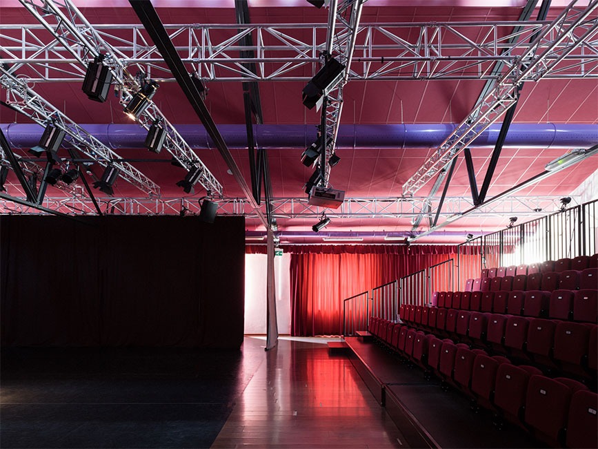 Pildil on teatri PimOff saali külgvaates. Paremas küljes on näha viis rida punaseid publikutoole, vasakul tumeda põrandaga lava.