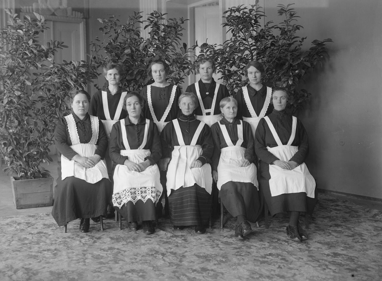 Mustvalgel pildil poseerivad 1925. aastal Estonia teatris töötanud publikuteenindajad. Pildil on üheksa naist, esimeses reas istub viis ja teises reas seisab neli. Neil on seljas tumedad pikad kleidid, mida katavad valged põlled.