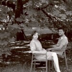 Mustvalgel fotol istuvad Livia Ulman ja Andris Feldmanis toolidel puu all. Ulman kannab heledat kleiti, Feldmanis ruudulist särki ja tumedaid pükse.