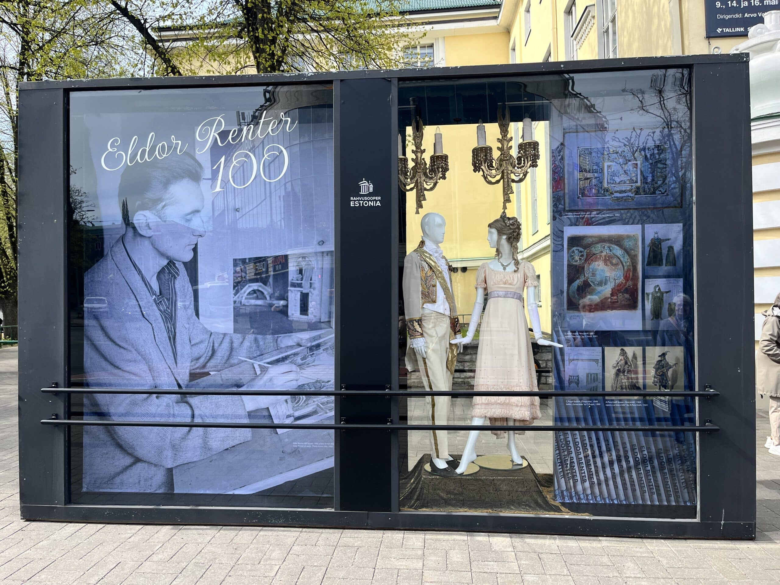 Pildil on väljapanek Eldor Renteri loomingust Rahvusooper Estonia ees. Tegu on suure vitriiniga, mille vasakul küljel on pilt Eldor Renterist ja paremal kaks mannekeeni teatrikostüümidega, nende kõrval fotod ja kavandid.
