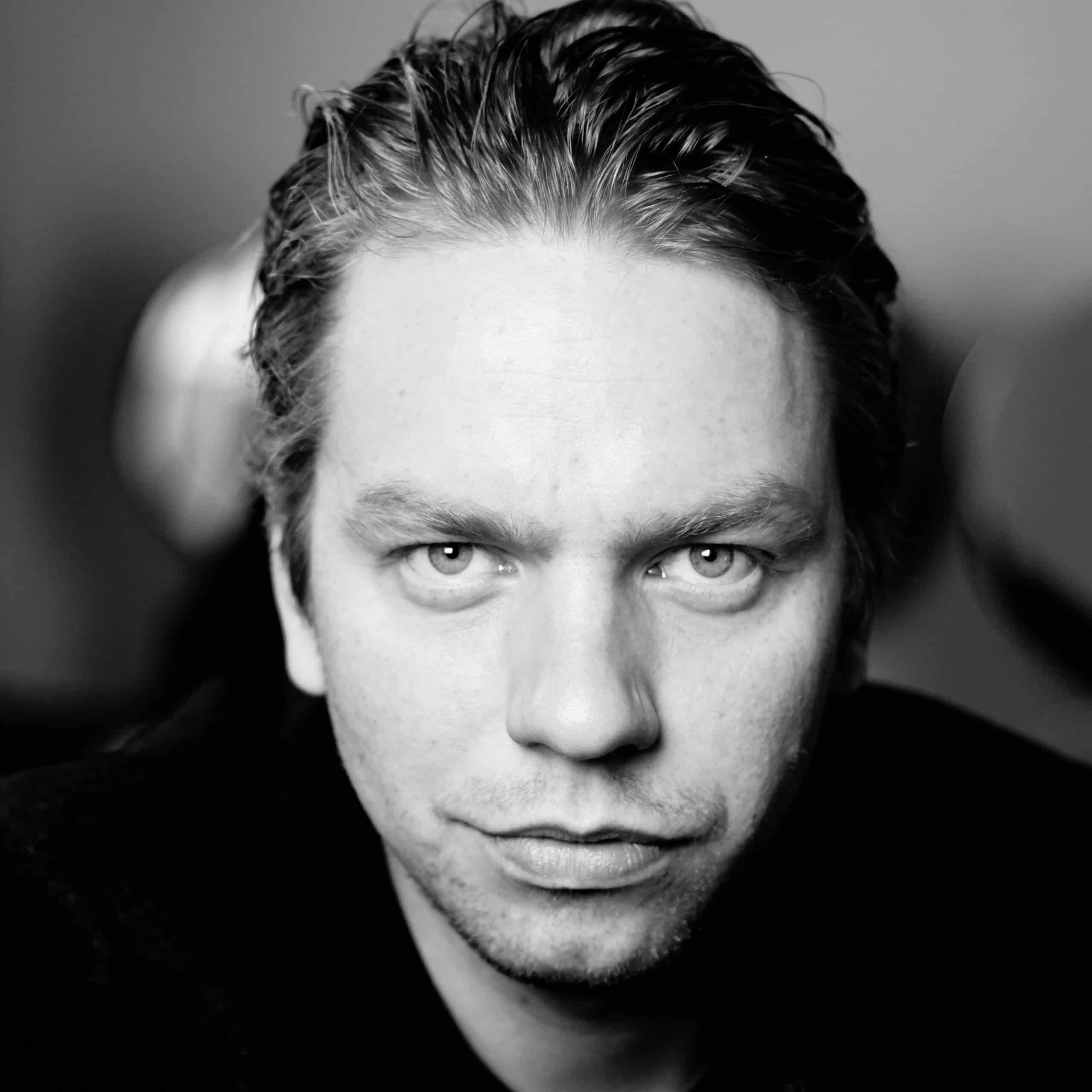 Mustvalgel portreepildil on Jörgen Liik. Tal on lühikesed tahapoole kammitud juuksed, heledad kulmud ja hele lühike habe.