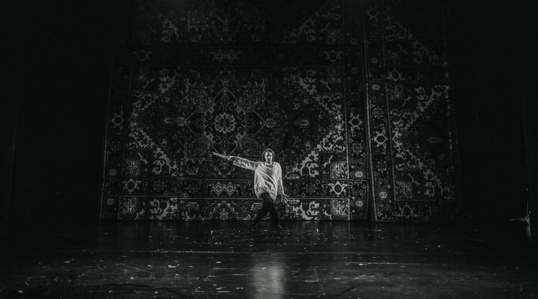 Mustvalgel fotol on Juhan Ulfsak, kes seisab Eesti Draamateatri suurel laval pärsia vaipa meenutava kardina ees. Tal on seljas lohvakas valge pikkade varrukatega särk ja tumedad püksid.