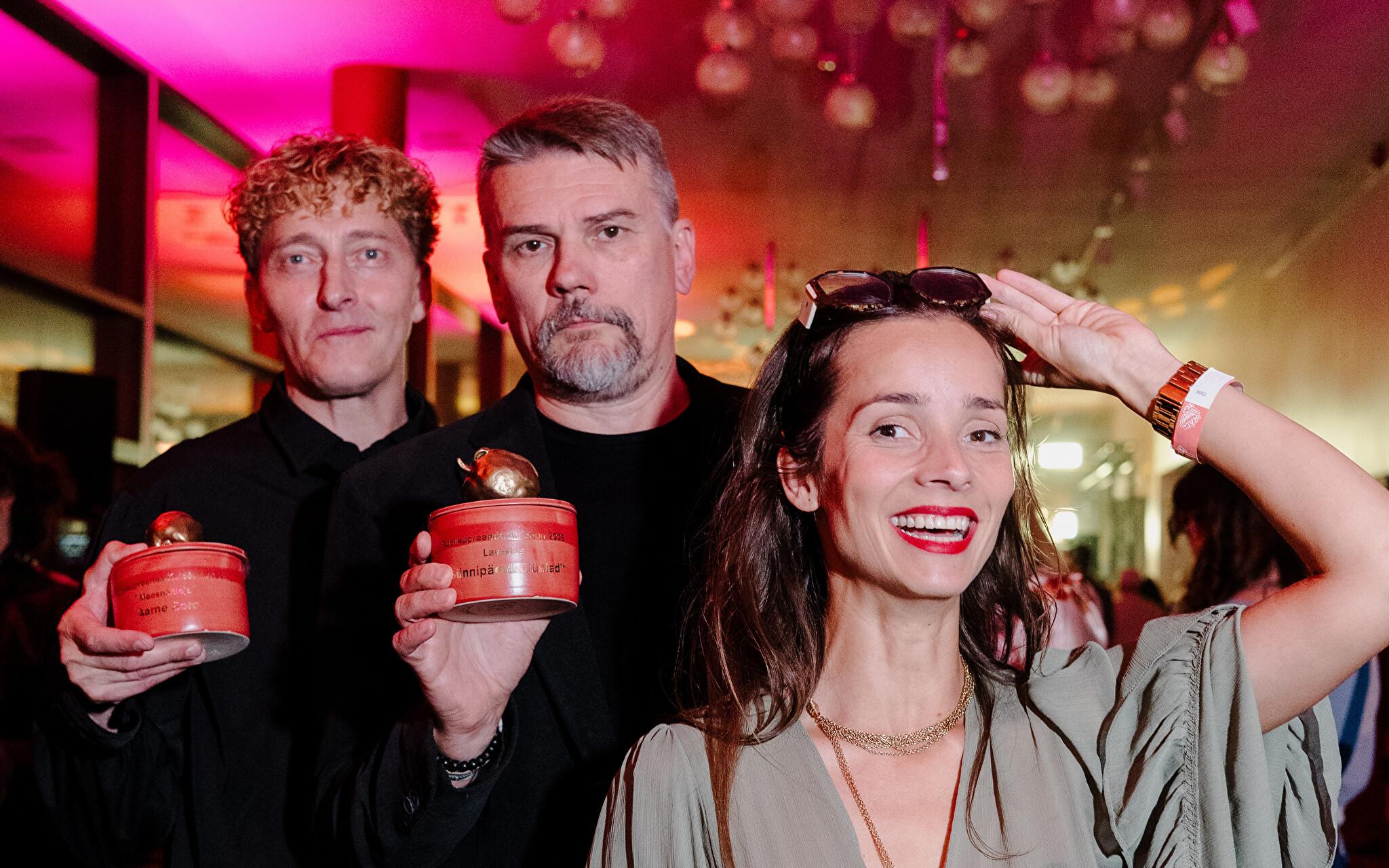 Pildil seisavad Aarne Soro, Andres Noormets ja Klaudia Tiitsmaa punakalt valgustatud Ugala Teatri fuajees. Soro ja Noormets hoiavad käes punaseid Kuldõuna auhindu.