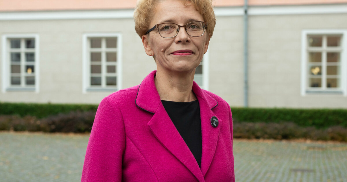 Pildil on Anneli Saro. Tal heledad lühikesed juuksed, pruunikate raamidega prillid ja seljas ereroosa jakk, mille all paistab must pluus.