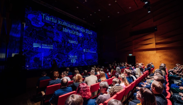 Pildil on Heino Elleri muusikakooli suur saal, kus istub punastel toolidel publik ning laval on sinine ekraan tekstiga 