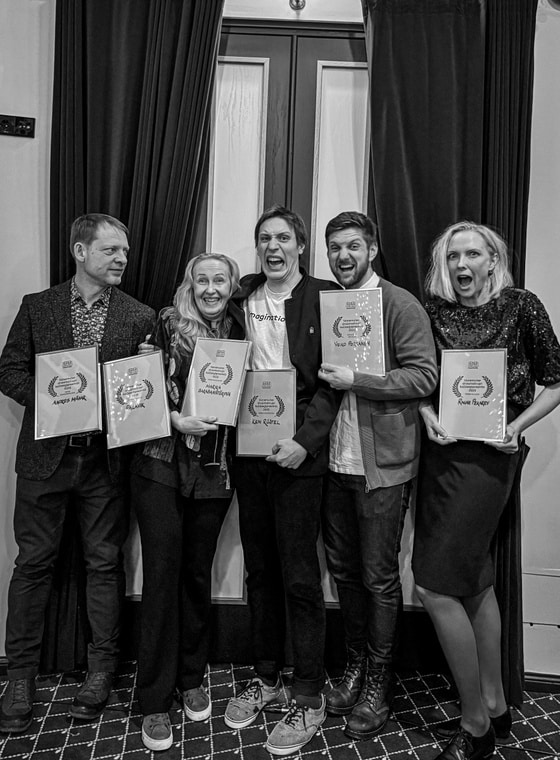 Mustvalgel pildil seisavad kõrvuti Andres Mähar, Marika Barabanštšikova, Ken Rüütel, Veiko Porkanen ja Ragne Pekarev, kes hoiavad käes raamitud diplomeid. Nende taga paistavad tumedad sametkardinad ja uks.