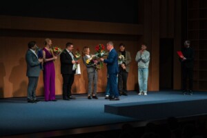 Pildil seisab Vanemuise teatri suure maja laval reas kaheksa inimest ning Verni Loodmaa ulatab neile lilli.