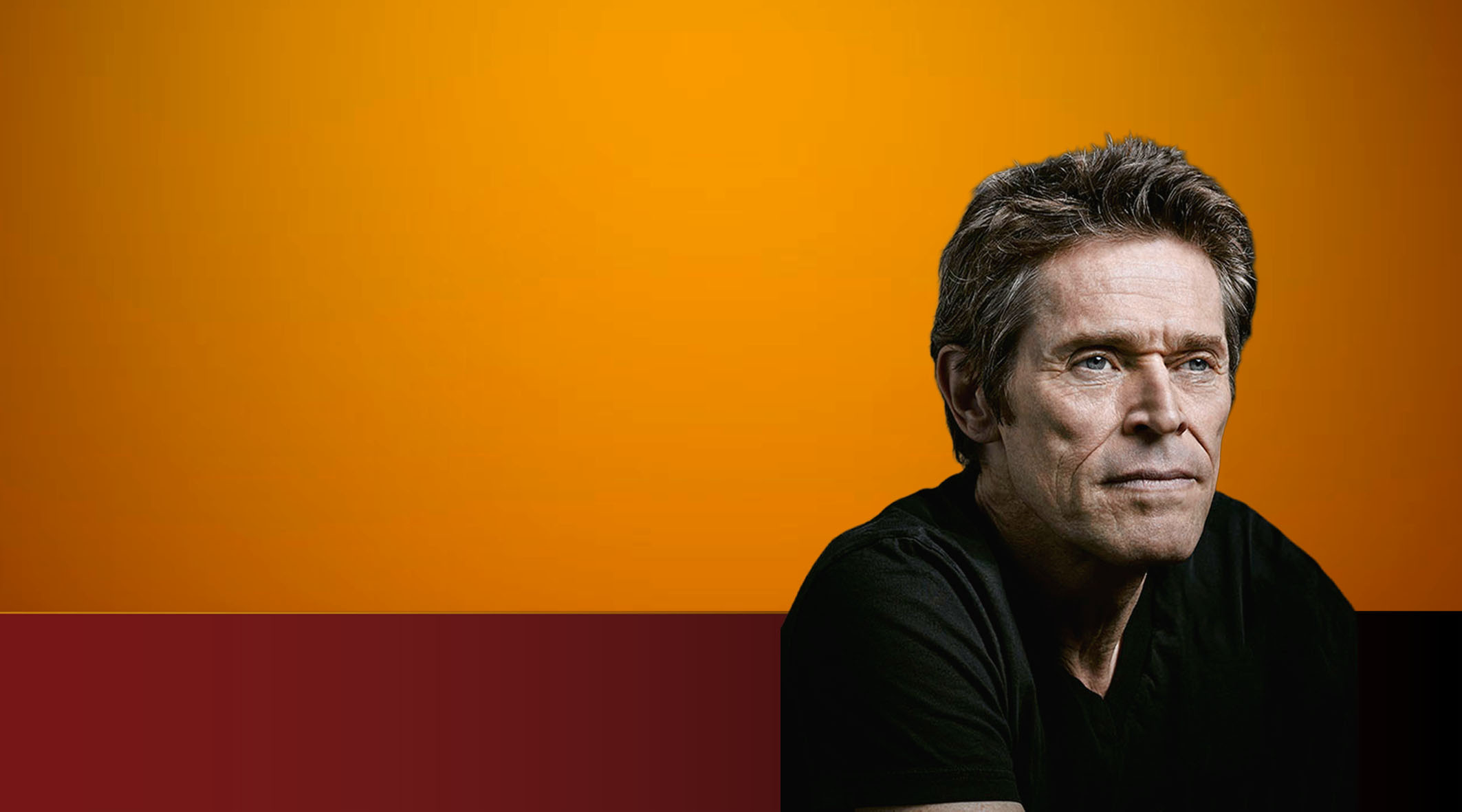 Pildil on näitleja Willem Dafoe oranžil ja tumepunase tausta ees. Ta on vanem mees, lühikeste tumedate juustega ning kannab seljas musta T-särki.