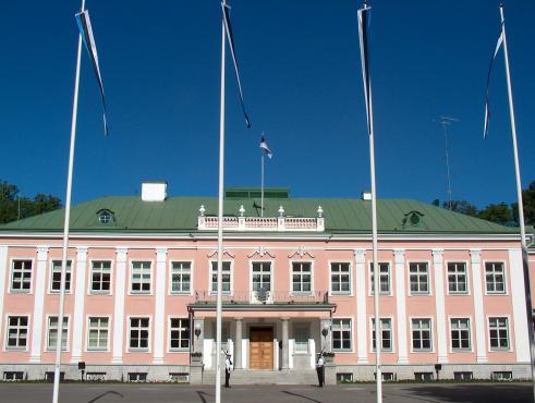Pildil on Kadrioru loss, kahekorruseline heleroosa hoone roheka katusega. Hoone ees on neli lipumasti.