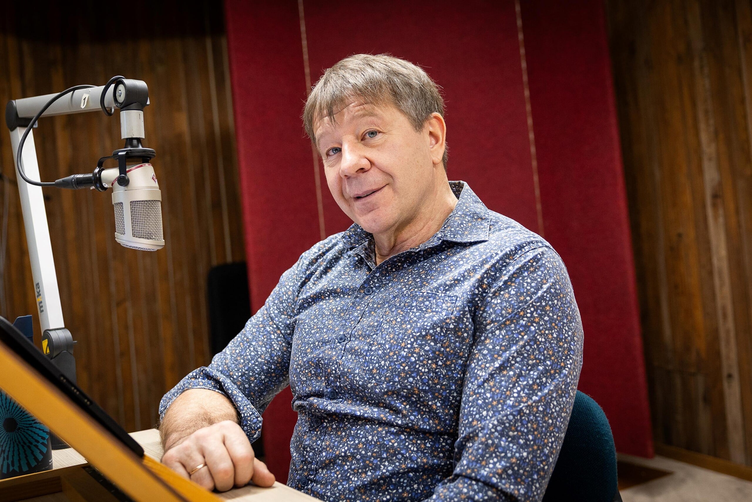 Pildil istub Marko Matvere helistuudios mikrofoni taga. Tal on lühikesed helepruunid juuksed ja seljas sinisekirju pikkade varrukatega triiksärk.