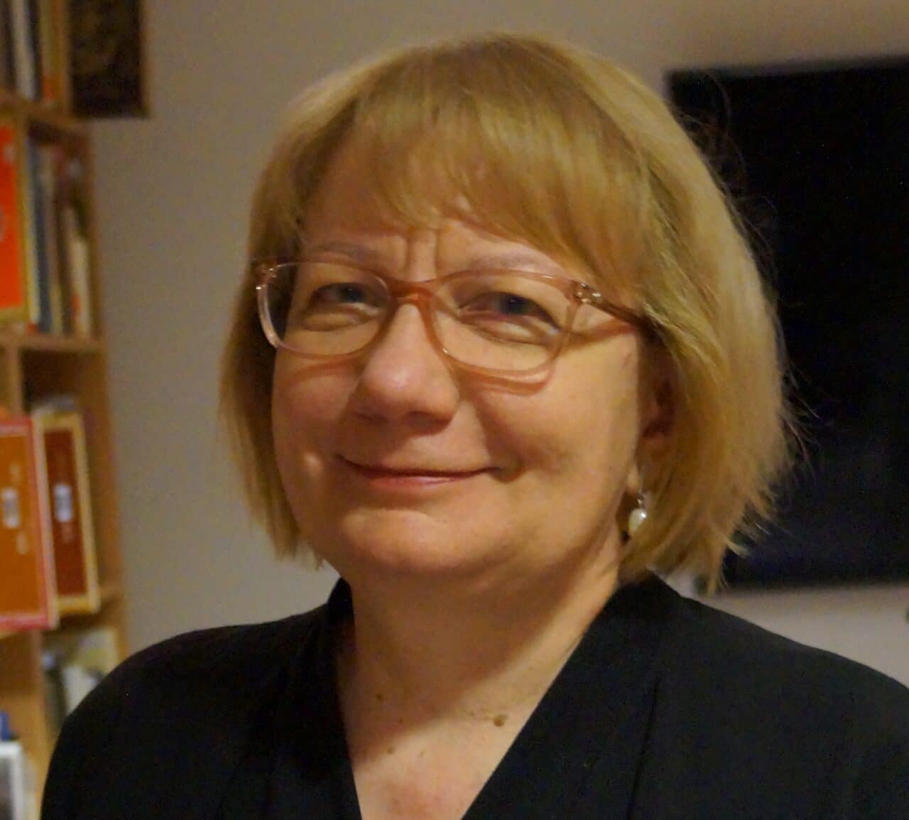 Portreepildil on Kristel Pappel, tal on lühikesed heledad juuksed ja heledate raamidega prillid. Ta naeratab ja vaatab kaamerasse.