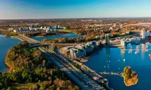 Pildil on vaade Espoo linnale, kus paistavad järved, metsad, maantee ning elu- ja ärihooned.