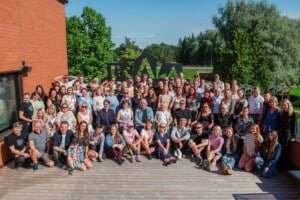 Esileht Pildil on Ugala Teatri kollektiiv, kes seisab ja istub Ugala Teatri kohviku terrassil. Nende taga paistab telliskividest sein, suur Ugala logo ja rohelus.